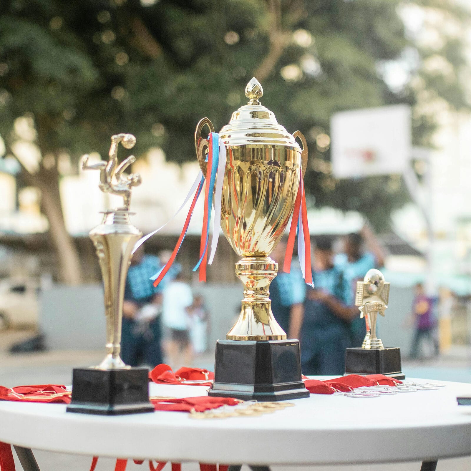 Copas y trofeos dorados con medallas en un evento deportivo al aire libre
