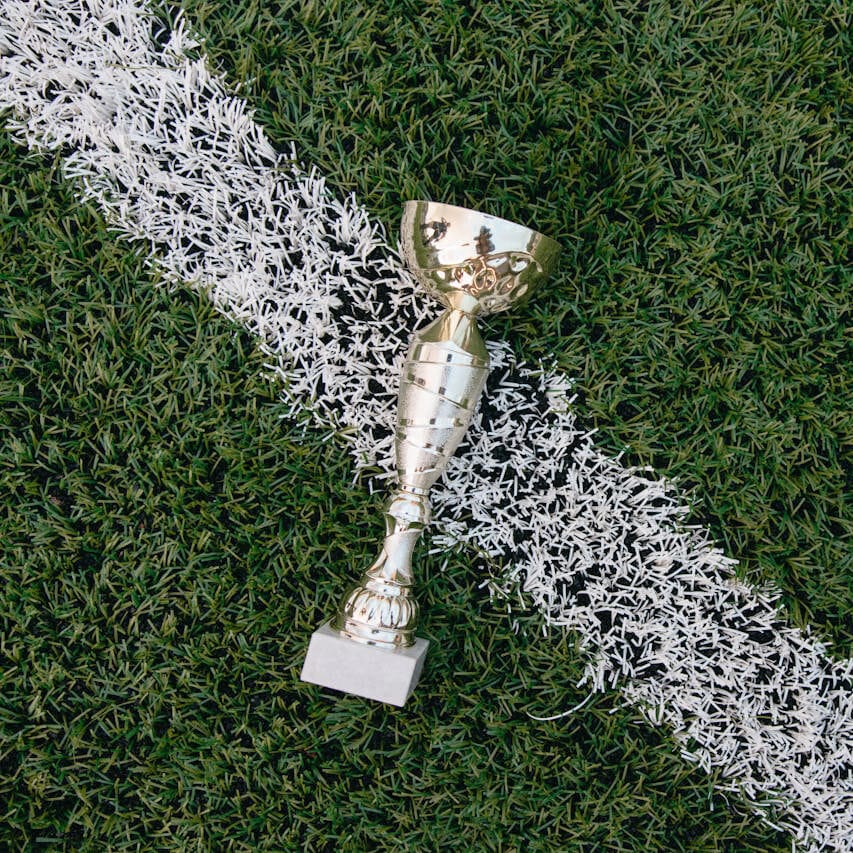 Copa de trofeo dorada sobre la línea de un campo de fútbol de césped